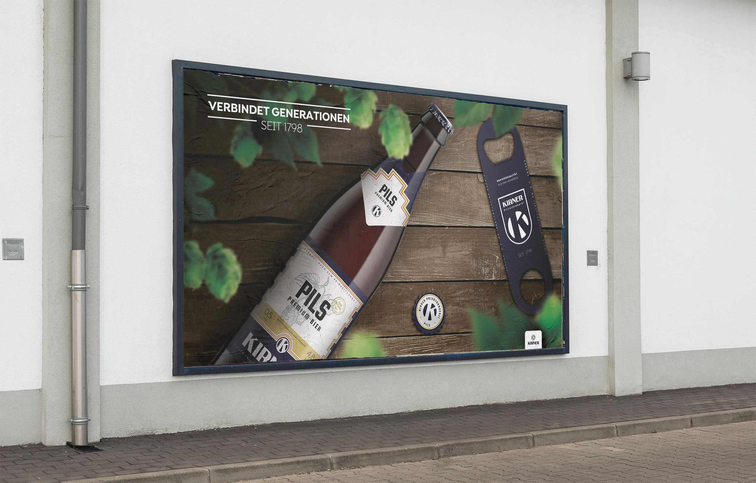 Großformatwerbung an Hauswand - Kirner Pils Flasche Draufsicht auf Holzboden durch Hopfen mit slogan