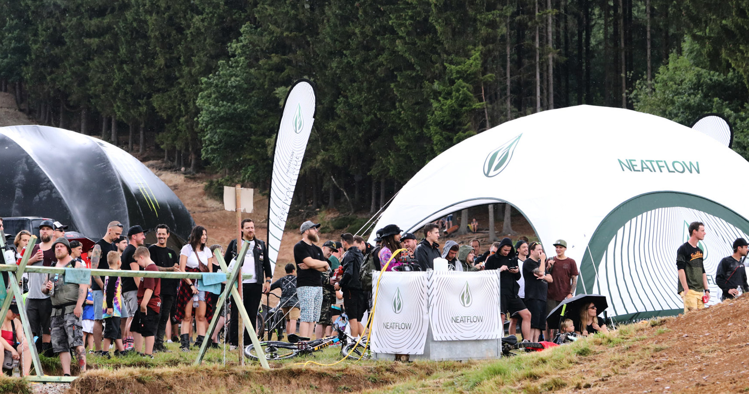 Panoramafoto - Messestand von Neatflow mit Beachflags - weißes Zelt und Waschstation - LooseFest Malmedy Bikepark